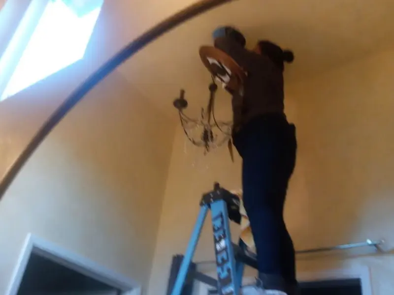 Electrician installing a chandelier in a Forest residence